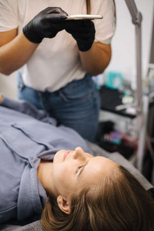 Female making photo of her client in beauty studio. Before after eyelash laminationの写真素材