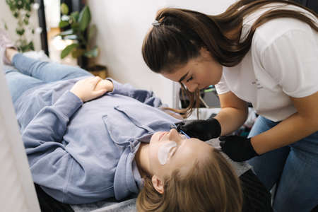 Beautician making eyelash lamination procedures for young model. Modern eyelash care procedures laminating and extension for lashes. Professional beauty studio.の写真素材