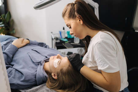 Beautician making eyelash lamination procedures for young model. Modern eyelash care procedures laminating and extension for lashes. Professional beauty studio.の写真素材