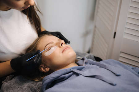 Attractive blond hair model in beauty studio having eyelash lamination. Modern useful procedure for lashesの写真素材