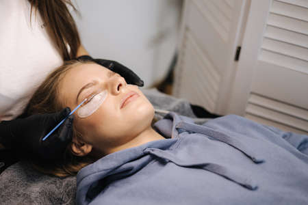 Attractive blond hair model in beauty studio having eyelash lamination. Modern useful procedure for lashesの写真素材