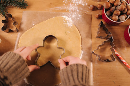 Woman making gingerbread at home. Female cutting cookies of gingerbread dough. Christmas and New...