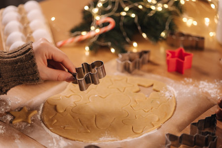 Woman making gingerbread at home. Female cutting cookies of gingerbread dough, view from above. Top...