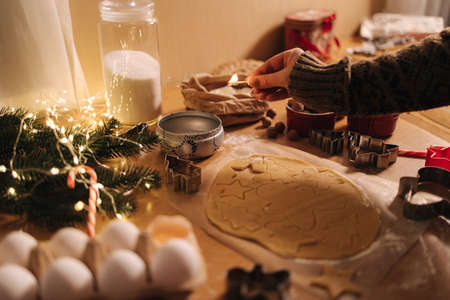 Woman lights a candle on Christmas. Preparing for baking gingerbread. Christmas moodの写真素材