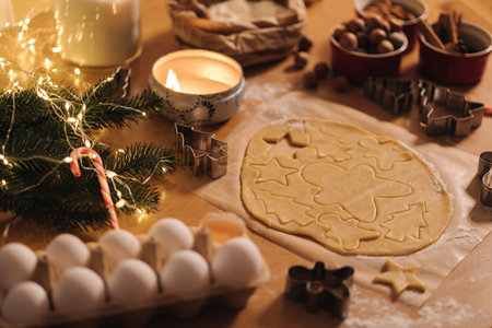 Raw dough for cooking Christmas cookies gingerbread on wooden table. Candle light at evening time