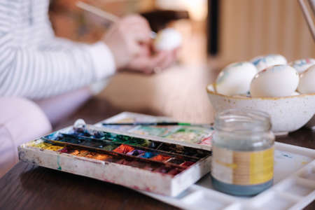Process of woman paiting a water colors on fantasy chicken eggs. Female preparing for Easter egg festivalの写真素材