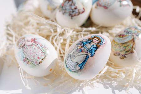 Close-up of different drawings on goose eggs for Easter festival. Eggs on hay. Hand made print. Spring hollidays. Easter conceptの写真素材