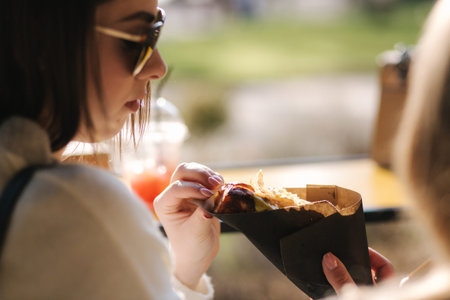 Tasty hot-dog in females hands. Girls buy street food. Daily routines on lunch break.