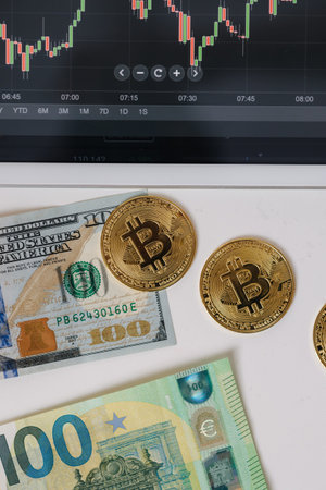 Golden bitcoin coin US dollar and euro near tablet with trading app. Stock market concept