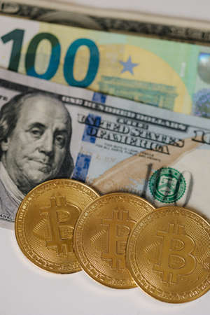 Close up of golden bitcoin lying on different banknotes. Cryptocyrrency compare with new virtual money. US dollar euro and other cashの写真素材
