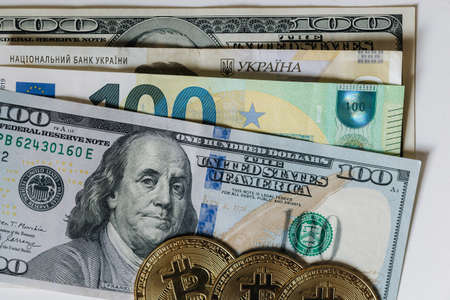 Golden bitcoin lying on different banknotes. Cryptocyrrency compare with new virtual money. US dollar euro and other cashの写真素材