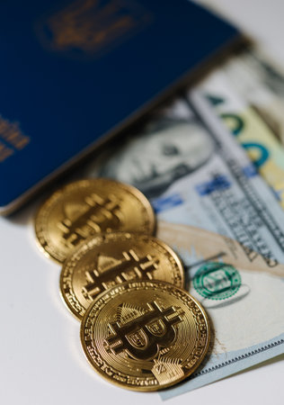 Urkainian passport with bitcoin golden coins and different banlnotes. US dollars and euro cash near the passport. Urkaine currency during the warの写真素材