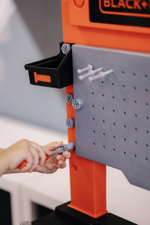 Little boy is playing with childrens tools and screwing a toy bolt with a screwdriver