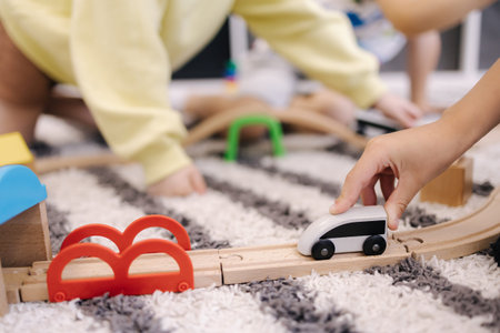 Little boy holds a toy train in hands and rides it on a wooden rail
