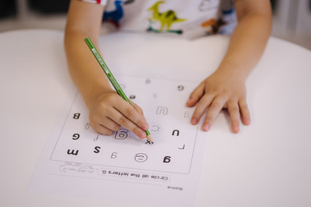 Children in the kindergarten circle different letters with a pencilの写真素材