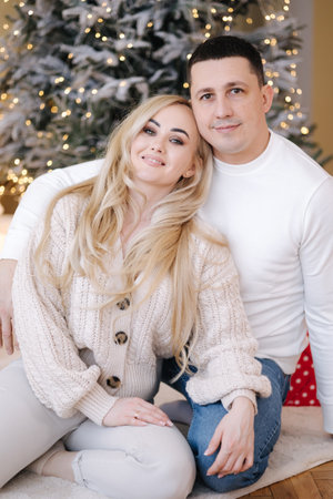 Gorgeous woman with her husband posing to photographer at home. Christmas mood. Background of lights.の写真素材