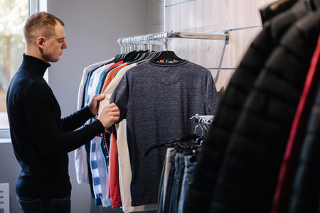 Half body shot of handsome customer choosing clothes. Man choose shirt in clothing storeの写真素材