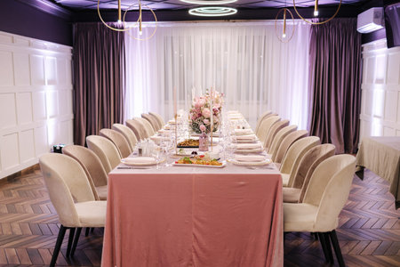 Elegant decoration of the table in restaurant. Pink tablecloth stylish cutlery and beautiful flowers