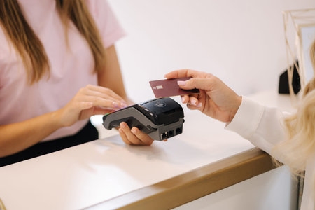 Female customer pay for procedures in beauty studio. Close-up of womans hand hold credit card