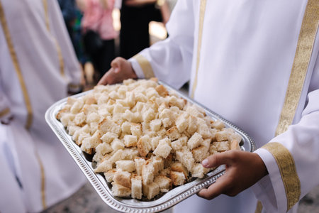 Brother priest hold a tray with bread cubes. First communion