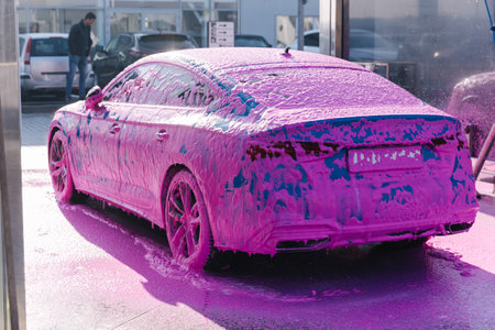 Luxury sport blue car on self servise car washing. Pink foam on auto. Back viewの写真素材