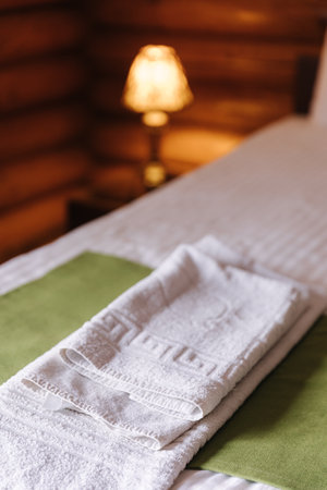 Hotel room in a wooden house. Authentic and stylish interior. A folded towel on the bed for visitorsの写真素材