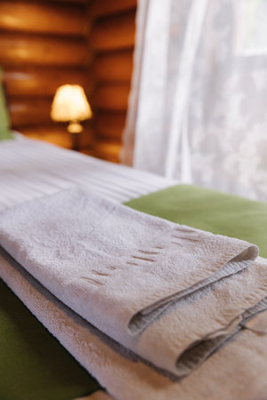 Hotel room in a wooden house. Authentic and stylish interior. A folded towel on the bed for visitorsの写真素材