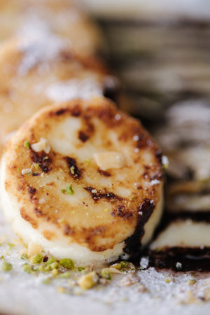 Macro photo cheesecakes fried in butter with creamy chocolate cream, grated nuts on topの写真素材