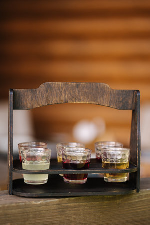 Multicolored alcoholic tinctures in 30 milliliter glasses on a wooden stand. Transcarpathian culture Ukraineの写真素材