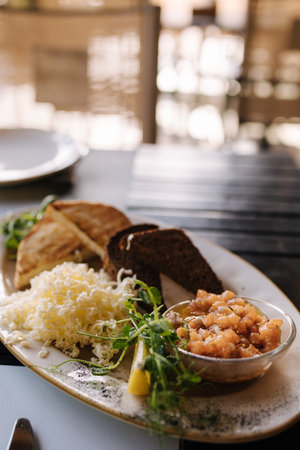 Salmon tartare served with grated butter and roasted bread. Table with food on terraceの写真素材