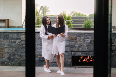 Two beautiful woman in white robe preparing for hot tube bathing. Relax outdoor in luxury resortの写真素材