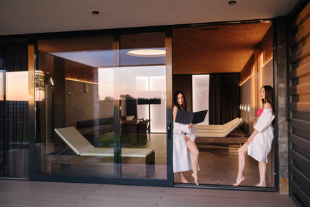 Two gorgeous female in luxury resort have rest after sauna. Woman in white bathrobeの写真素材