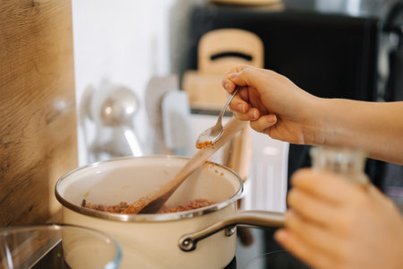 Close-up of woman adds spicy seasoning. Home made food concept. Kitchenの写真素材