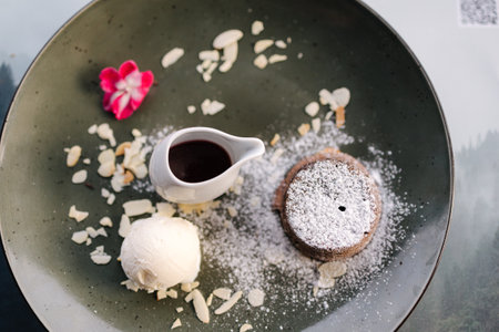 Top view of chocolate fondant with scoop of ice cream, blackberry syrup and slices of almondの写真素材