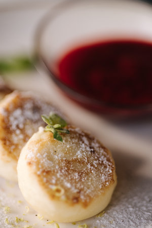 Curd fritters decorated powdered sugar in plate. Cheesecake, fresh jam, sour cream and mint.の写真素材
