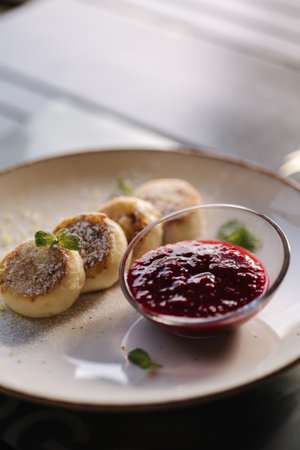 Curd fritters decorated powdered sugar in plate. Cheesecake, fresh jam, sour cream and mint.の写真素材