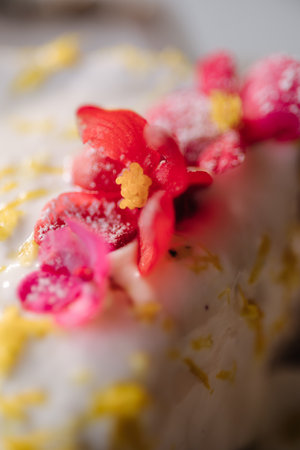 Macro photo of cheesecake with sweet cream sauce and lemon zest, decorated with an edible pink flowerの写真素材