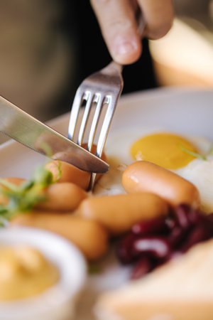 Macro photo of man slice sausage. English breakfast outdoor. Lunch in restaurant. Foodの写真素材