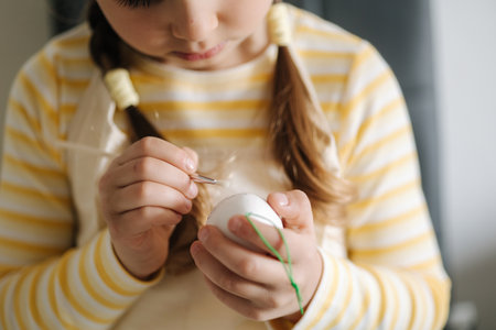 Easter holiday at home, adorable little girl painting eggs in kitchen. Focus on hands. Close-upの写真素材