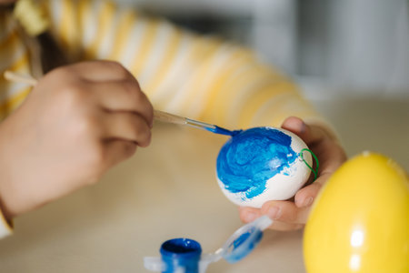Macro photo of little girl growing easter eggs on kitchen. Yellow and blue colour. Ukrainian symbolicの写真素材