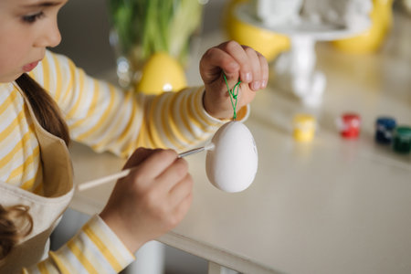 Macro photo of little girl growing easter eggs on kitchenの写真素材