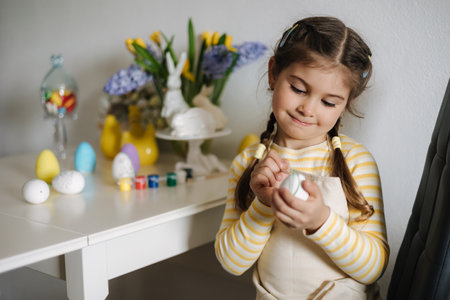 Easter holiday at home, adorable little girl painting eggs in kitchen. Girl smile and drawの写真素材