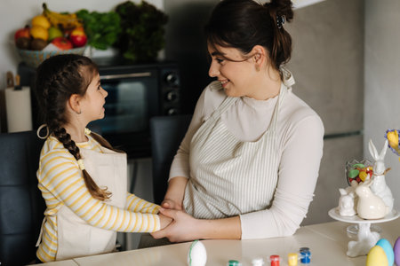 Cute little girl with her mother preparing for painting easter eggs. Mom and daughter look to each otherの写真素材