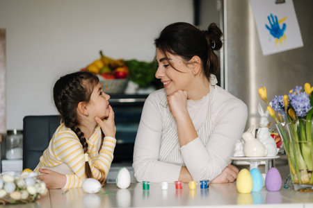 Cute little girl with her mother preparing for painting easter eggs. Mom and daughter look to each otherの写真素材