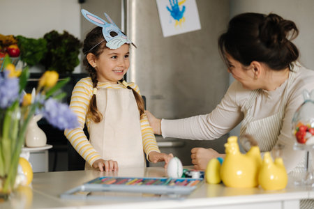 Mom take off the Easter bunny mask from her daughters face to see her beautiful smileの写真素材