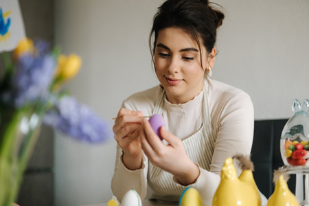 Attractive young woman painting Easter eggs in the kitchen. Spring holidays.の写真素材