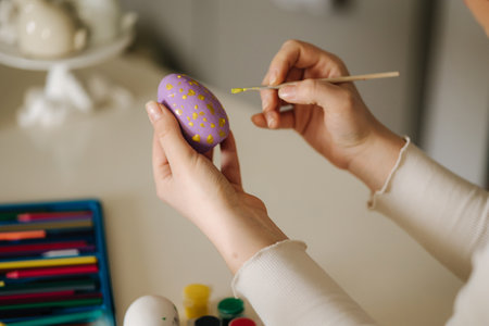 Close-up of woman painting Easter eggs in the kitchen. Spring holidays.の写真素材