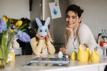 Cute little girl put on an Easter bunny mask. Happy mom smiling. Holidayの写真素材