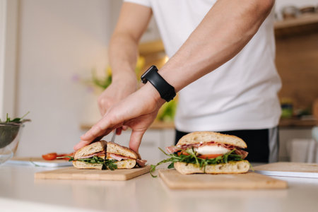 Middle selection of handsome young man slice Italian sandwich in the kitchen. Close-up of bruschetta in handsの写真素材