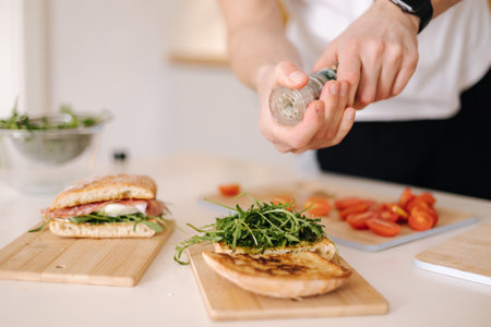 Man using pepper grinder for preparing tasty sandwich at home. Middle selectionの写真素材